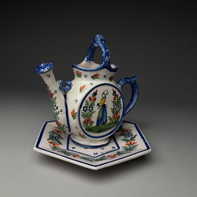 une théière et une soucoupe posées sur une assiette, sur une table