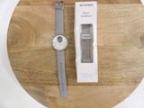 a white watch sitting on top of a wooden table next to a box