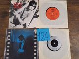 four records on a wooden table with a blue label and a picture of a man
