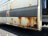 rust on the side of a bus parked on the side of the road