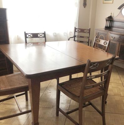 une table et des chaises dans une pièce où est accrochée une horloge au mur