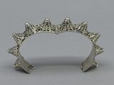 a silver bracelet with a crown on top of it on a gray surface