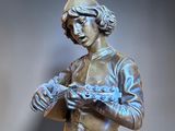 a bronze statue of a woman holding something in her hands
