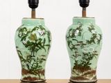 une paire de vases verts décorés d'oiseaux et de fleurs, posés sur une table