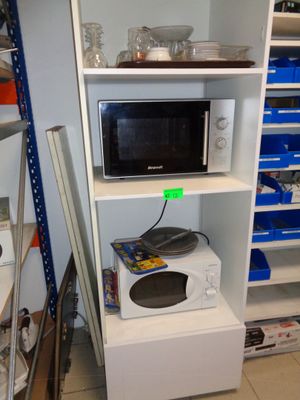 un micro-ondes posé sur une étagère dans un coin de la pièce
