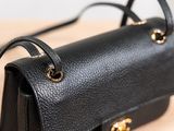 a black purse with gold hardware on a wooden table