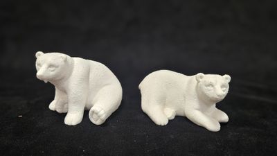 pair of white ceramic polar bear figurines on a black background