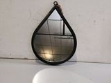 un miroir noir en forme de larme posé sur un comptoir blanc