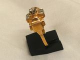 an image of a gold and diamond ring on a black stand