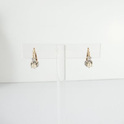 une paire de boucles d'oreilles posée sur un présentoir, sur fond blanc