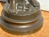 une statue en bronze représentant un garçon avec un livre posé sur une table