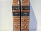 two old books are sitting on a white surface with a white background