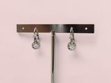 une paire de boucles d'oreilles suspendues à une tige métallique devant un mur rose