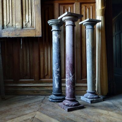 trois piliers dans une pièce dont les murs sont revêtus de boiseries