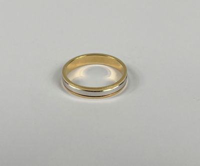 gros plan d'une bague en or et en argent sur une surface blanche
