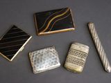 trois types différents d'étuis à cigarettes et un briquet posés sur une table