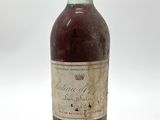 une vieille bouteille de vin posée sur une surface blanche