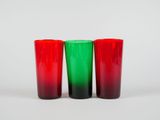 three red and green glasses sitting next to each other on a white surface