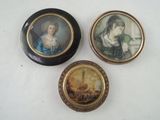 three miniature paintings of women are displayed on a white surface