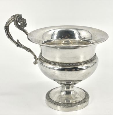 une coupe en argent ornée d'une poignée en forme de dragon, posée sur un socle