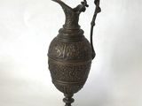 une image représentant un vase en métal muni d'une anse, sur fond blanc