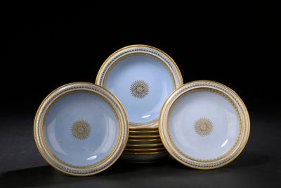 quatre assiettes bleues et blanches à bord doré, posées sur un fond noir
