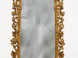 un miroir richement sculpté, doté d'un cadre doré et posé sur un socle