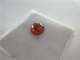 an orange diamond sits on a white cloth on a white surface
