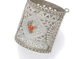 an image of a silver cuff with a red stone in the center