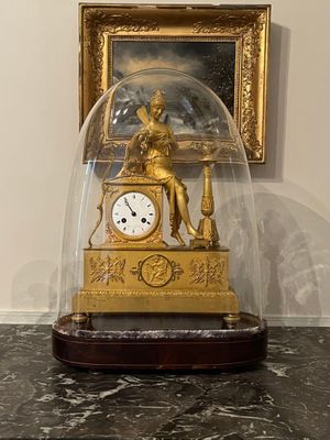 une horloge en or sous un dôme de verre, posée sur une table en marbre