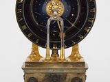 une horloge posée sur un socle orné d'un oiseau
