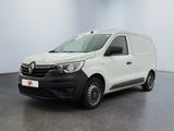 La camionnette blanche est garée dans une grande pièce au sol noir.