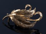 an image of a gold leaf broochle on a black surface
