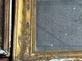 two gold framed mirrors sitting on the floor next to each other