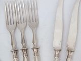 four forks and a knife on a table with a white table cloth