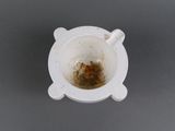 a white cup with a brown substance in it on a gray surface
