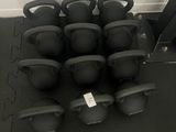 de nombreux kettlebells noirs posés sur un tapis noir