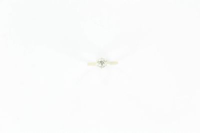 une photo d'une bague sertie d'un seul diamant posée sur une surface blanche