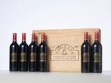 four bottles of red wine in a wooden box on a table