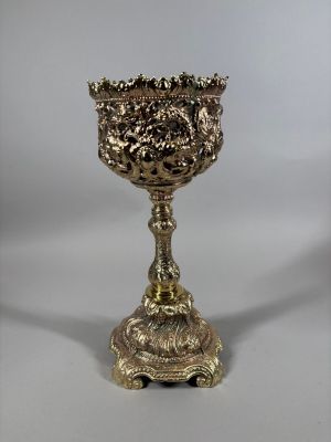 une coupe ancienne en métal argenté sur un socle, sur fond blanc