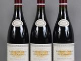 three bottles of red wine are lined up on a table