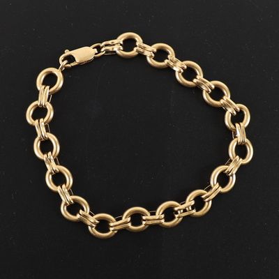 un bracelet en chaîne dorée orné d'un pendentif en forme de cœur sur fond noir