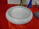 a white bowl sitting on a red table next to a blue vase