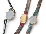 three different colored watches on a white surface with a black strap