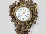une horloge dorée accrochée au mur, sur fond blanc