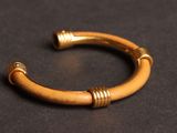 a close up of a gold bracelet on a black surface