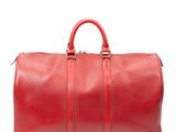 un sac de voyage rouge posé sur une surface blanche