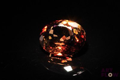 a close up of an orange diamond on a black surface