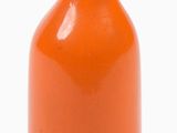 an orange vase that is sitting on a white surface