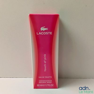 un flacon de parfum rose Lacoste posé sur une table